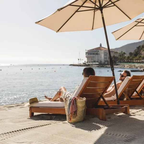 Two people relaxing on lounge chairs at Descanso Beach Club.