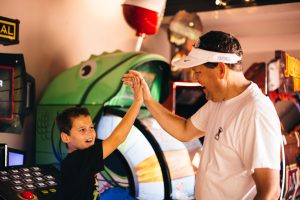 A father and son high fiving at the Three Palms Arcade.