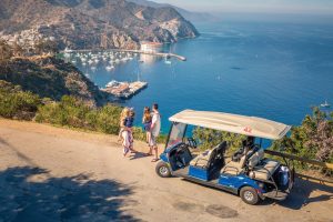 A family driving a golf cart around Avalon.