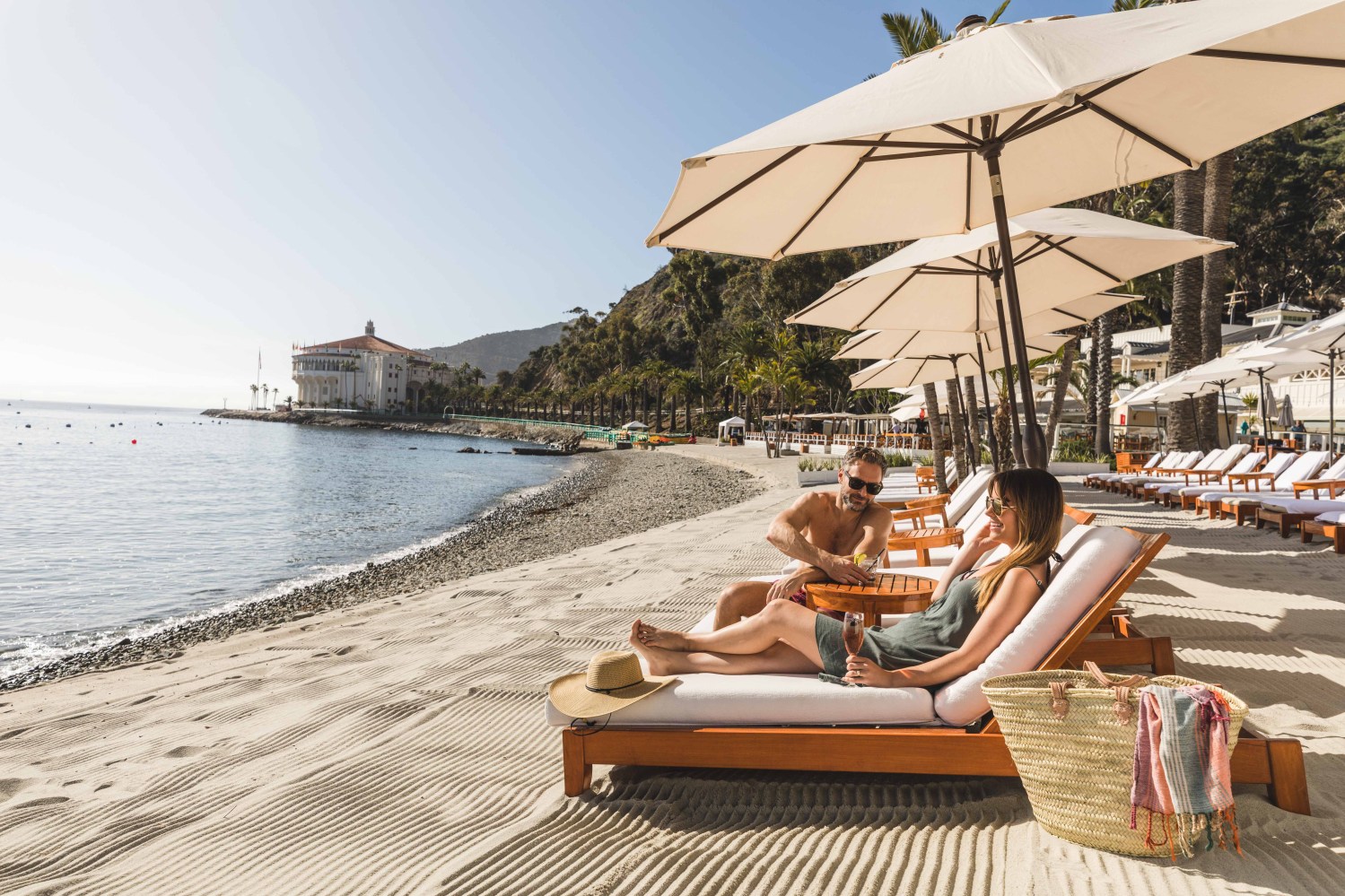 A couple sitting on chaise lounge chairs at the Descanso Beach Club.