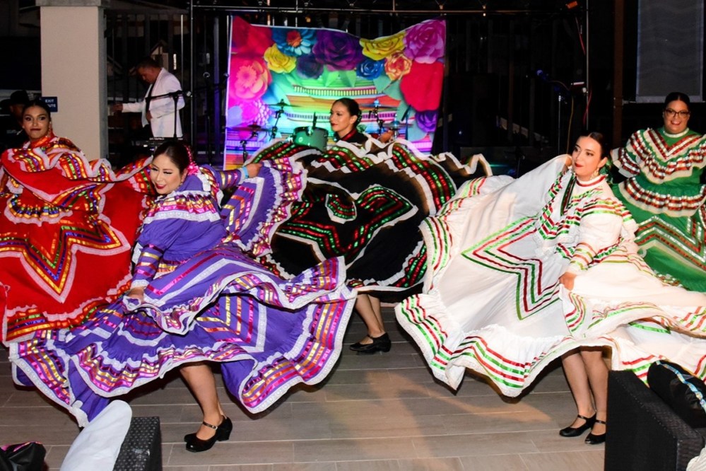 Dancers in colorful traditional dresses perform lively onstage.